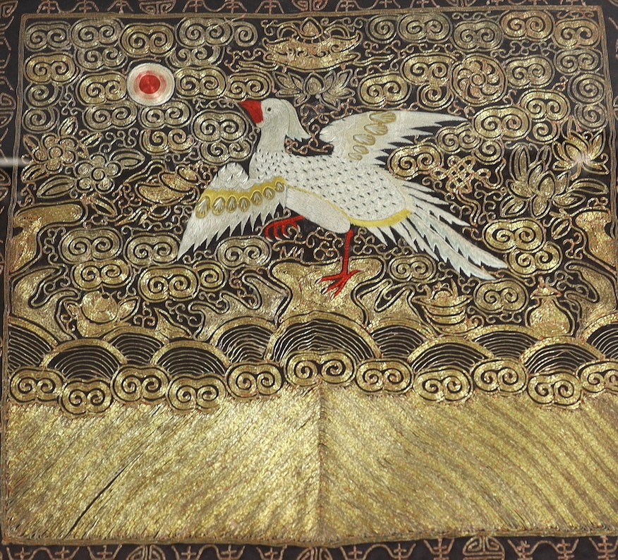 A Chinese silk ornately coloured and gold thread embroidered rank badge, of a Phoenix, 32cms wide x 29cms high